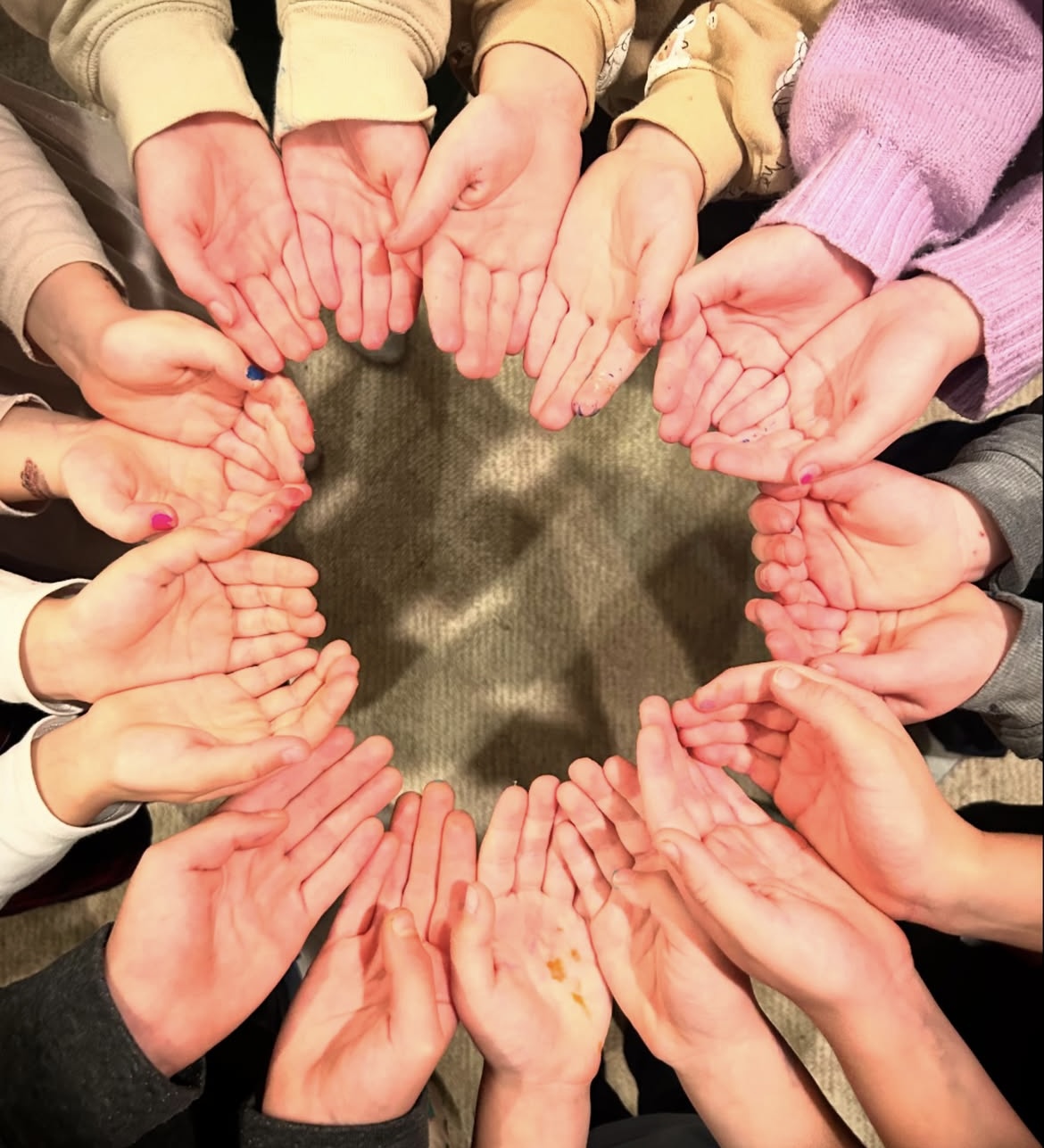 Children's hands forming a circle together at Little Blueprints Art Studio
